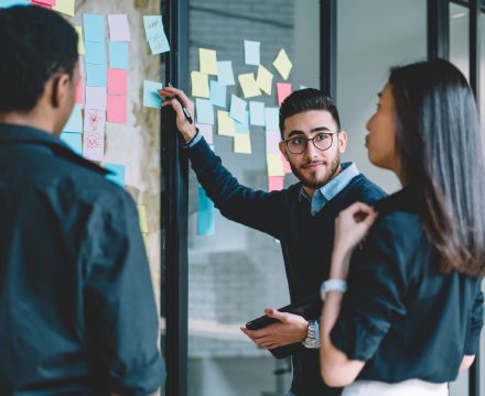 Founders brainstorming with sticky notes on a glass office wall