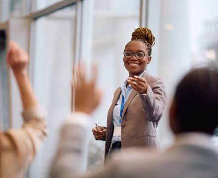 Leader taking questions from an engaged team with raised hands